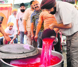 Devotees make sweetened cold water in the memory of Guru Arjun Dev in Mandi on Wednesday. 