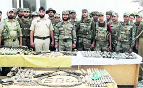 Police and Army personnel display a cache of arms and ammunition recovered from a forest in Bandipore district on Wednesday
