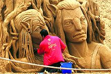 An artist works on two characters of the Avatar movie at the annual Sand Sculpture Festival in coastal town of Blankenberge, Belgium, on Wednesday