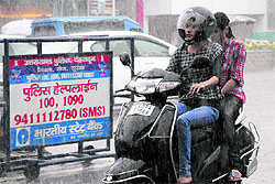 Two girls move on a scooter as it rains heavily in Dehradun on Thursday