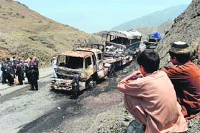 Pakistani security personnel gather beside torched NATO supply trucks after an attack by armed militants in Khyber district