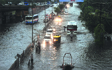 Vehicles move at a snails pace with headlights on during heavy rain at Dholewal Chowk in Ludhiana on Thursday morning; and (below) a portion of a road that caved in front of Dhami Eye Hospital in the city.