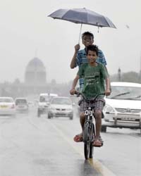 SUNNY SPIRIT: Children enjoy cycling during the rains at Rajpath in New Delhi on Friday