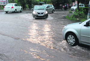 Vehicles pass through a flooded road at Sector 20 in Panchkula on Saturday. 