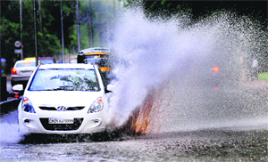 A car zooms through a waterlogged road near Panjab University.