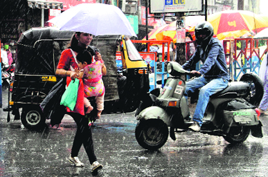 A woman protects herself and her baby from rain in Dehradun on Saturday.