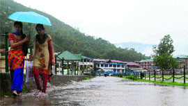Students walk through a water-logged road in Mandi on Saturday.