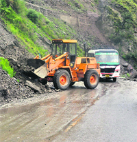 A JCB machine clears a highway following heavy downpour in the Jammu-Doda region on Saturday.