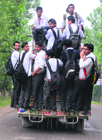 Schoolchildren cling on to an overcrowded bus in north Kashmirs Bandipora district on Saturday. 