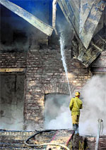 A firefighter extinguishes a blaze which gutted a historical building in Ziarat on Saturday.  AFP