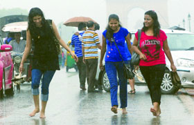 Girls enjoy themselves in the rains at Rajpath near India Gate in New Delhi on Sunday.