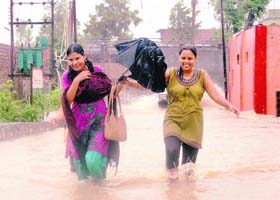 Two girls wade through knee-deep water in the Clementown area