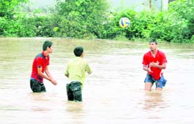 Three youths play volleyball in water in Dehradun