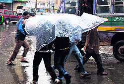 Men run for cover during a spell of rainfall in Srinagar on Sunday