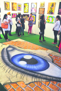 Visitors take a look at paintings during an exhibition at Gallery Artmosphere in Ludhiana. 