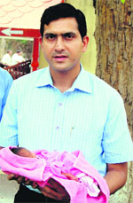 Deputy Commissioner Rajat Aggarwal holds the baby boy left in the Pangura at Red Cross Bhavan in Amritsar on Monday.