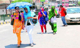 Girls use an umbrella to protect themselves from heat near Bathinda Railway Station on Tuesday afternoon.