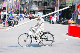 A man travels on a bicycle carrying a long pole-like object in the city on Tuesday.