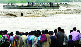 People gather near Old Iron Bridge which submerged in the Yamuna in New Delhi on Tuesday.