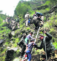 Army personnel rescue stranded children and other pilgrims to a safe place in the flood-hit Gobind Ghat in Chamoli on Tuesday.  PTI 