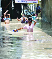 People carry the bare essentials as they wade through the rising waters of the Yamuna at the Tibetan market in New Delhi on Wednesday. 