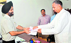 Brijender Ola, Rajasthan Disaster Relief Minister, hands over a cheque to S.S.Sandhu, Principal Secretary to Uttarakhand Chief Minister, in Dehradun on Wednesday