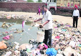 A health worker uses the dip-stick method after the electrical spray pump developed a snag during a drive to control water-borne diseases in rain-affected areas in Jalandhar on Thursday