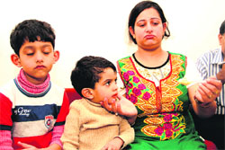 A woman with her children, who were rescued from Harsil at Uttarkashi district, in Dehradun on Friday.