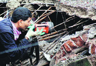 A rescue worker searches for people stuck in the debris of the collapsed building.