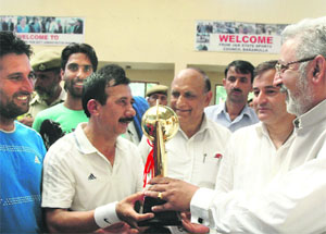 Minister for Medical Education, Youth Services and Sports Taj Mohi-ud-Din presents the trophy to Baramulla badminton team in Srinagar on Friday. 