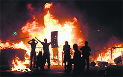 Demonstrators stand next to a fire during a protest rally, part of what is now called the 'Tropical Spring' against corruption and price hikes, in Rio de Janeiro on Friday