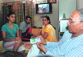 Sudesh Vashist with his family shows pictures of flood-hit areas after returning home at Sector 10 in Panchkula on Saturday