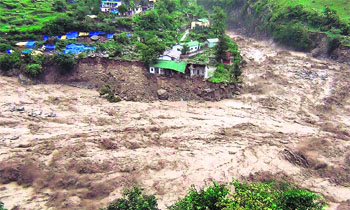  Houses perched precariously along a river in spate. 