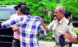 A police official rounds up students after a clash outside an examination centre