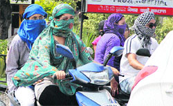 Girls ride a scooter covering their faces in Jalandhar as heat wave intensified.