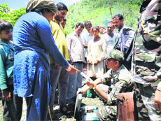 An Army officer provides relief material to evacuated people at Kalapani.