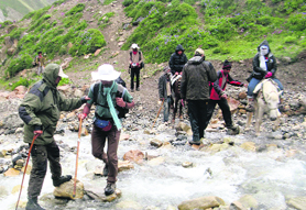 Army officials help Kailash Mansarover pilgrims to cross a stream near Kalapani in Pithoragarh.