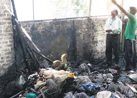 A shopkeeper assesses loss as a short-circuit triggered a fire engulfing three shops near new Railway Road in Gurgaon on Monday