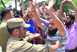 Policemen stop National Youth Corps volunteers as they shout slogans during a protest in Srinagar on Monday. Tribune Photo: Amin War