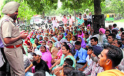 A policeman tries to pacify Dera Sacha Sauda followers outside the Dugri police station in Ludhiana
