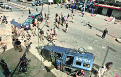 Security men gather at the site of a bomb blast in Karachi on Wednesday.  AP/PTI
