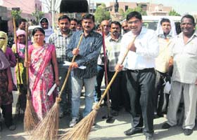 SDM Vivek Chaudhary (in white shirt) sweeps a road with a broom while launching a special cleanliness drive in Gohana