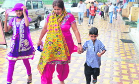 A woman with her children caught in the rain in Srinagar on Thursday.