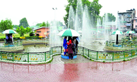 Youngsters take shelter under a sunshade as it rains in Srinagar.