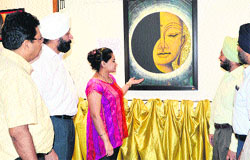 Visitors take a look at a painting at an exhibition in the Sutlej Club, Ludhiana, on Friday. A Tribune photograph