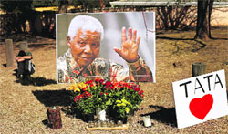 A boy sits near a picture of Nelson Mandela near the Union Building in Pretroria on Friday.  AP/PTI