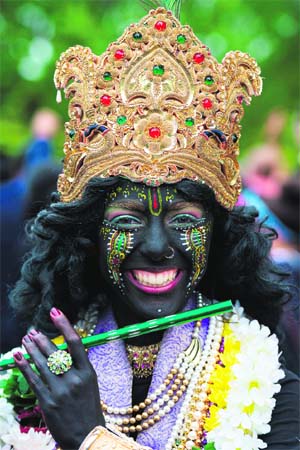 A child dressed as Lord Krishna poses for a photograph during a rath yatra