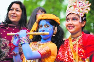 Devotees dressed in costumes to represent Lord Krishna (C) and his consort Radha (R) during a rath yatra, as the procession travels through Central London