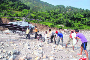 People offload relief material from a helicopter in Sodhi village near Augustmuni on Sunday. The village has been cut off from other areas due to damaged roads.