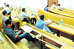 Aspirants appear for the NET on broken benches at the University of Jammu on Sunday